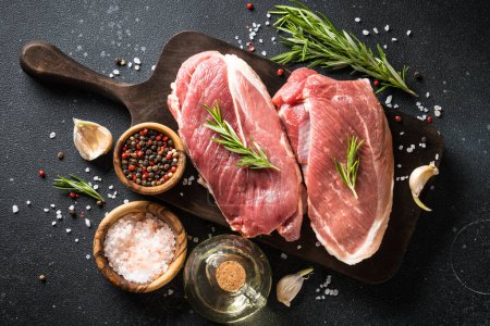 Photo for Raw meat steaks with spices at dark background. Flat lay. - Royalty Free Image