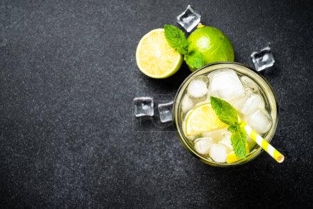 Photo for Mojito with rum, lime, mint and ice on black background. Tradition Summer drink. Flat lay. - Royalty Free Image