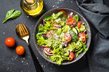 Téléchargez les photos : Salade de légumes verts avec des feuilles fraîches sur fond noir. Vue du dessus. - en image libre de droit