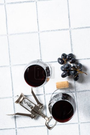 Téléchargez les photos : Verre à vin sur fond blanc. Deux verres avec raisin et tire-bouchon avec des ombres dures. - en image libre de droit