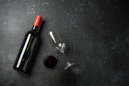 Botella de vino y copa de vino en fondo negro. Vista superior con espacio de copia.