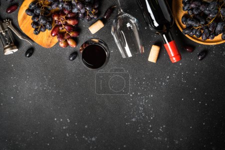 Photo for Red Wine at black background. Glass of wine, bottle, crape and corkscrew. Top view with copy space. - Royalty Free Image
