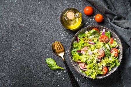 Téléchargez les photos : Salade de légumes verts avec des feuilles fraîches sur fond noir. Vue du dessus. - en image libre de droit