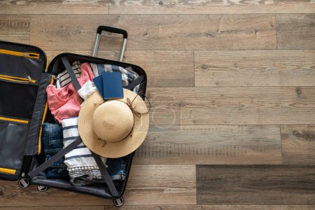 Foto de Maleta abierta con paño de verano, sombrero y pasaportes. Concepto de viaje. Imagen plana sobre fondo de madera. - Imagen libre de derechos