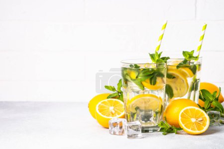 Photo for Lemonade in glass on white table with fresh lemons and mint. Cold summer drink. - Royalty Free Image