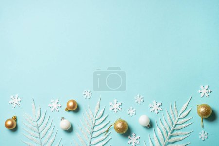 Téléchargez les photos : Décorations de vacances blanches et dorées sur fond bleu. Pose plate avec espace de copie. - en image libre de droit