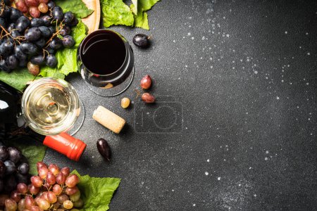 Photo for Red and white wine at black background. Glasses of wine, bottles and fresh crape. Top view with copy space. - Royalty Free Image