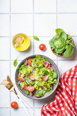 Téléchargez les photos : Salade de légumes verts aux feuilles fraîches. Vue de dessus sur fond de tuiles blanches. - en image libre de droit