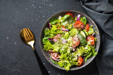 Téléchargez les photos : Salade de légumes verts avec des feuilles fraîches sur fond noir. Vue du dessus avec espace pour le texte. - en image libre de droit