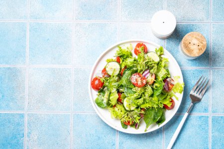 Téléchargez les photos : Salade de légumes verts avec des feuilles fraîches sur assiette blanche. Aliments sains, menu diététique. Vue du dessus avec espace pour le texte. - en image libre de droit