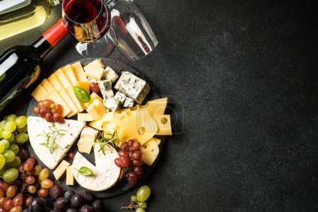 Photo for Cheese platter and red wine. Craft cheese set with grape on slate board. Top view at black background. - Royalty Free Image