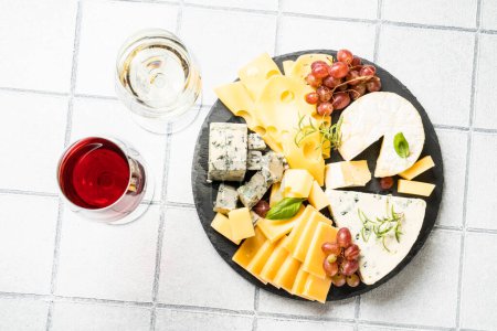 Photo for Cheese platter with craft cheese assortment and wine glasses at white tile background. Top view. - Royalty Free Image