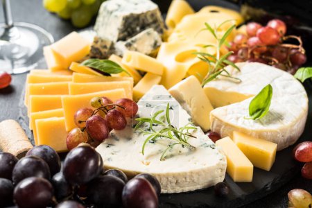 Téléchargez les photos : Plateau de fromage avec assortiment de fromages artisanaux et raisin sur planche d'ardoise. - en image libre de droit