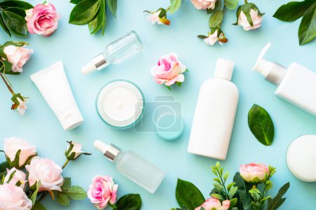 Photo for Natural cosmetic products on blue background. Cream, serum, tonic with green leaves and flowers. Skin care concept. - Royalty Free Image