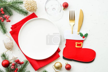 Photo for Christmas table setting. White plate, cutlery, red and golden decorations. Top view at white table. - Royalty Free Image
