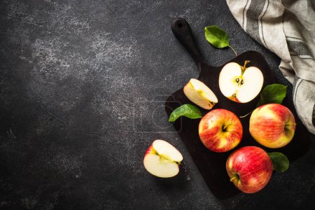 Foto de Manzanas frescas maduras, manzanas enteras y cortadas en rodajas en la mesa de piedra negra. Vista superior con espacio de copia. - Imagen libre de derechos
