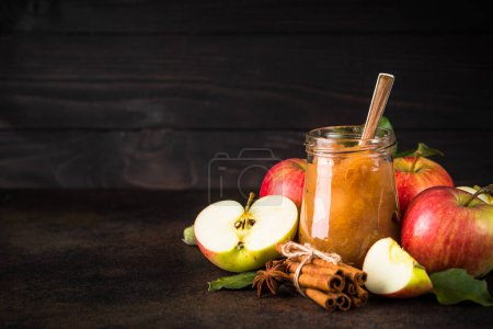 Foto de Mermelada de manzana con especias y manzanas frescas sobre fondo de piedra oscura. - Imagen libre de derechos