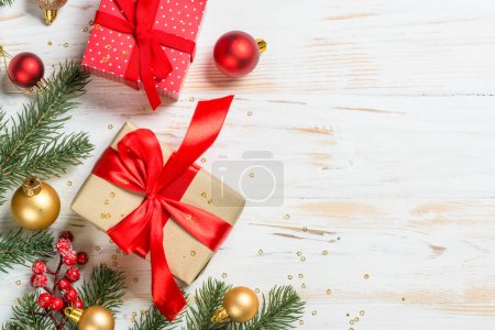 Photo for Christmas present box with red ribbon and holiday decorations. Top view at white wooden table with copy space. - Royalty Free Image