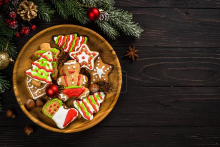 Photo for Christmas gingerbread in the plate with spices and decorations on dark wooden table. Christmas baking. Top view with copy space. - Royalty Free Image