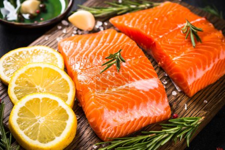 Téléchargez les photos : Du poisson frais. Filet de saumon cru à la planche à découper avec des ingrédients pour la cuisson. - en image libre de droit