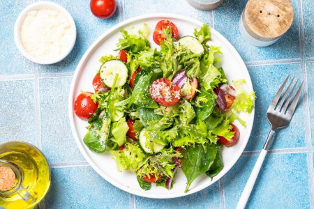 Téléchargez les photos : Salade de légumes verts avec des feuilles fraîches sur assiette blanche. Aliments sains, menu diététique. Vue du dessus avec espace pour le texte. - en image libre de droit