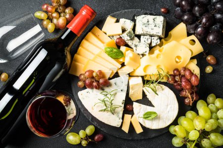 Photo for Cheese platter with craft cheese assortment on slate board and red wine at black background. Top view. - Royalty Free Image