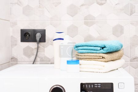 Téléchargez les photos : Serviettes propres et produits cosmétiques à la machine à laver dans la salle de bain. - en image libre de droit