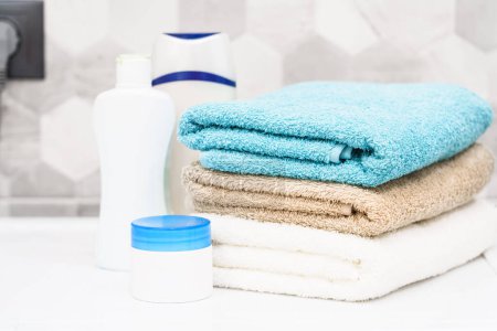 Téléchargez les photos : Serviettes propres et produits cosmétiques à la machine à laver dans la salle de bain. - en image libre de droit