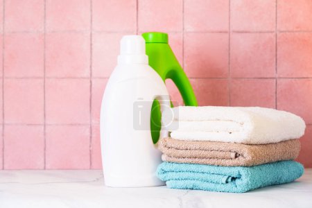 Téléchargez les photos : Serviettes propres et détergent gel de lavage dans la buanderie ou la salle de bain contre le mur de tuiles. - en image libre de droit