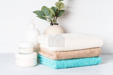 Téléchargez les photos : Produits cosmétiques et serviettes propres dans la salle de bain. Soins spa et produits de beauté. - en image libre de droit