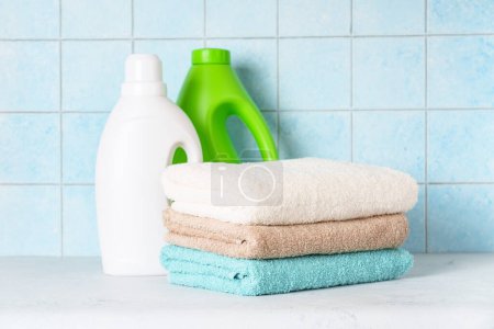Foto de Toallas limpias y detergente en la lavandería o el baño contra la pared azul. - Imagen libre de derechos