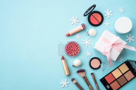 Photo for Winter cosmetic with present box and holiday decorations on blue. Christmas sale and gift concept. Flat lay with copy space. - Royalty Free Image