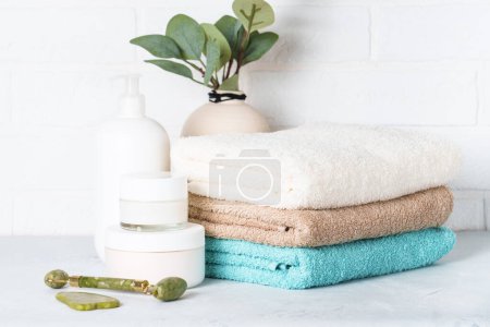 Photo for Cosmetic products and clean towels in the bathroom. Spa treatment and beauty products. - Royalty Free Image