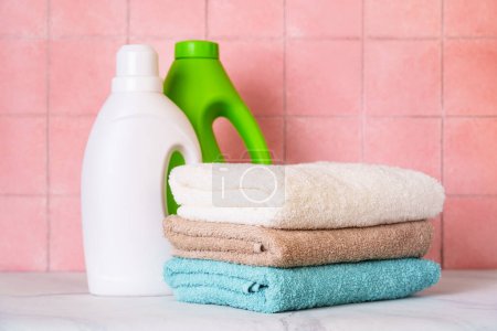 Téléchargez les photos : Serviettes propres et détergent gel de lavage dans la buanderie ou la salle de bain contre le mur de tuiles. - en image libre de droit