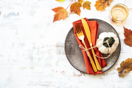 Foto de Ajuste de mesa otoño. Acogedoras decoraciones de otoño, placa artesanal y cubiertos dorados sobre fondo blanco. - Imagen libre de derechos