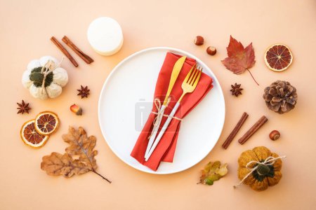 Photo for Autumn table setting. Cozy fall decorations, white plate and golden cutlery on color background. Flat lay. - Royalty Free Image