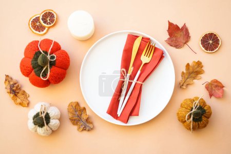 Photo for Autumn table setting. Cozy fall decorations, white plate and golden cutlery on color background. Flat lay. - Royalty Free Image
