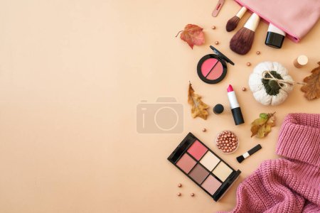 Foto de Productos cosméticos con tela y accesorios en el fondo de otoño. Suéter, bolsa cosmética y productos de maquillaje con hojas de otoño. Piso con espacio de copia. - Imagen libre de derechos