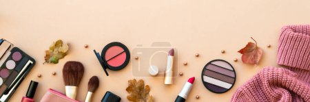 Photo for Autumn beauty background. Make-up products, knitted sweater and autumn leaves at pastel background. Long banner format. - Royalty Free Image