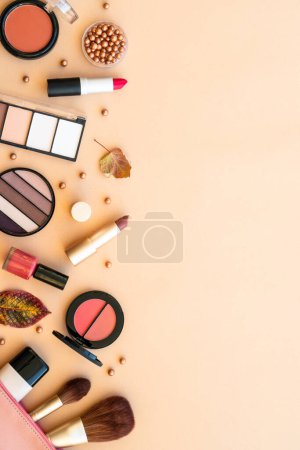 Photo for Make-up beauty products at pastel background with autumn decorations. Powder, foundation, mascara, lipsticks. Flat lay with space for text. - Royalty Free Image