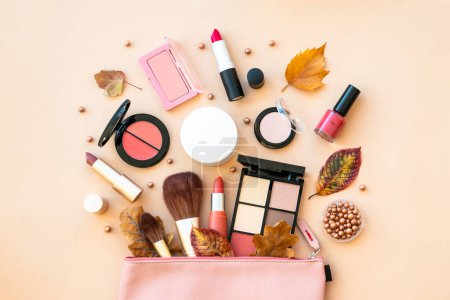 Photo for Autumn beauty background. Cosmetic bag with make-up beauty products and autumn leaves at pastel background. Flat lay with space for text. - Royalty Free Image
