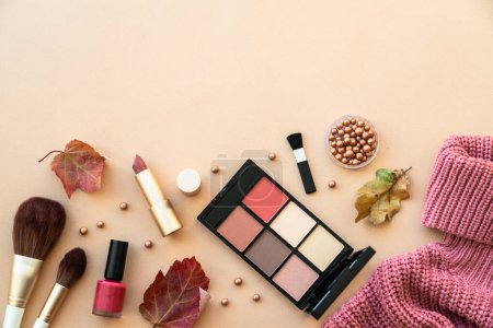 Photo for Autumn beauty background. Make-up products, knitted sweater and autumn leaves at pastel background. Flat lay. - Royalty Free Image