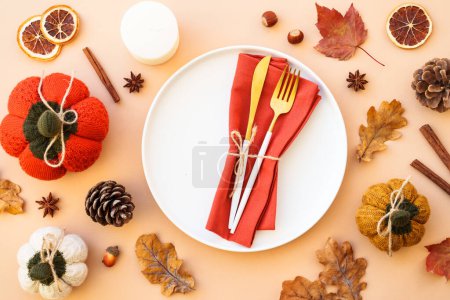 Téléchargez les photos : Fond alimentaire d'automne. Table de Thanksgiving. Assiette blanche et couverts dorés avec des décorations sur fond de couleur. Pose plate. - en image libre de droit