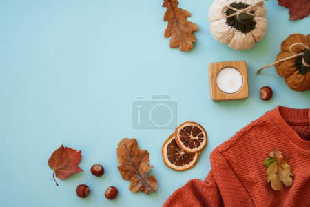 Photo for Warm sweater, autumn leaves, candle and decor on blue background. Flat lay image with copy space. - Royalty Free Image