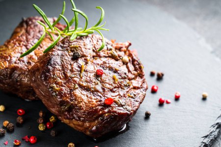 Photo for Meat steaks. Beef medallions with spices and herbs at stone board on black background. - Royalty Free Image