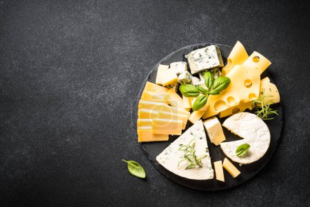 Photo for Cheese platter with craft cheese assortment on slate board at black background. Top view with copy space. - Royalty Free Image