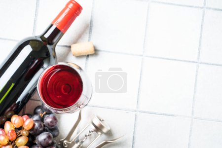 Photo for Red Wine at white background. Glass of wine, bottle, corkscrew and crapes. Top view with copy space. - Royalty Free Image