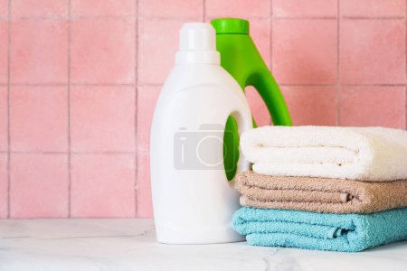 Foto de Toallas limpias y detergente en la lavandería o baño contra la pared de baldosas. - Imagen libre de derechos