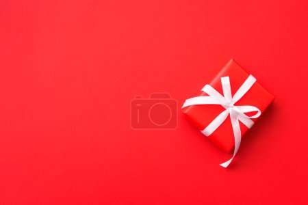 Téléchargez les photos : Coffret cadeau de Noël, cadeau rouge avec ruban à fond rouge. Image de pose plate avec espace de copie. - en image libre de droit