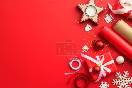 Téléchargez les photos : Noël Cadeau boîte et décorations à fond rouge. Emballage cadeau de Noël. Image de pose plate avec espace de copie. - en image libre de droit
